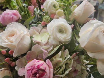 Arranged in a glass cube and filled with hydrangeas, garden roses, ranunculus, berries and peonies