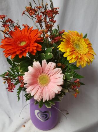 GERBERA DREAMS...3 bright gerbera daisies in a Heart Mason jar arranged with wax...if in season or baby's breath of not available.