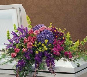 FOND REMEMBRANCE Half Casket Spray of purple delphinium, iris, bells of ireland, hydrangea, roses and more.