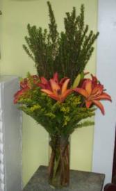 Contemporary Lilies cylinder vase of lilies with center of tall greens in a bed of Salidago