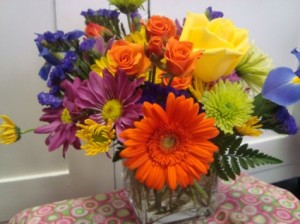 Small bright mixture of seasonal flowers for take  home in a rectangular vase.
