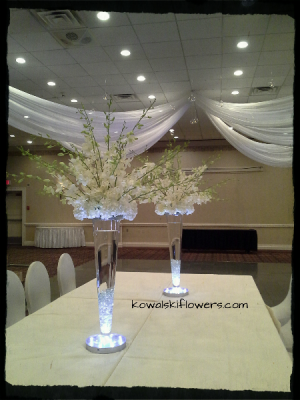 Guest table centerpiece on Eiffel Tower vase with white dendrobium orchids,  chrysanthemum…