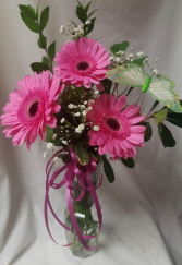 3 PINK GERBERA DAISIES WITH BOW AND BUTTERFLY IN A BUD VASE.