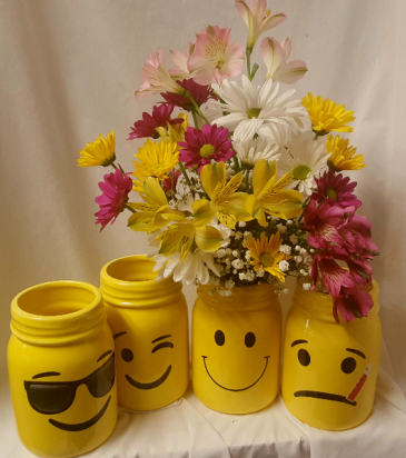 MASON JARS WITH FACES...WE WILL SELECT WHAT IS IN stock with the smiley versions. If you want the one for a get well just put that in the additional information area and we will select that one. ARRANGED with bright colored daisies, filler and astramaria lilies.