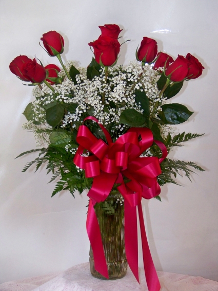 FOREVER YOUNG ROSES Classic dozen red roses in vase with filler, greens, and bow. 