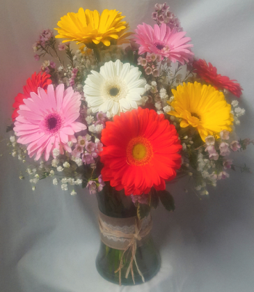 Large Gerberas arranged in a vase with filler and wax flowers.