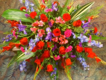 LOVING THOUGHTS Half Casket Spray of shades of blues, reds and purples. Roses delphinium, carnations, alstroemeria lillies, and more