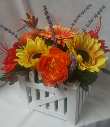 SILK BRIGHT FLOWERS ARRANGED IN WHITE Picket fence looking wood container. ARRANGED all the way around to make a nice centerpiece. Great for funerals, nursing centers, etc. With hummingbird too!