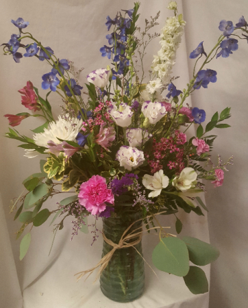 Large vase arrangement with shades of purples, blu and whites.