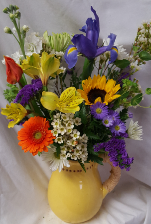 Ceramic pitcher with raffia wrapped handle filled With bright mixed seasonal flowers! (Pitcher colors may vary)