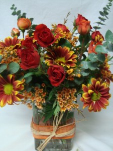 Orange and Red spray Roses with fall varigated daisies and wax flower all arranged in a rectangular vase!