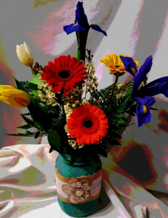 Mason Jar with lace filled with bright flowers. Vase color may vary.
