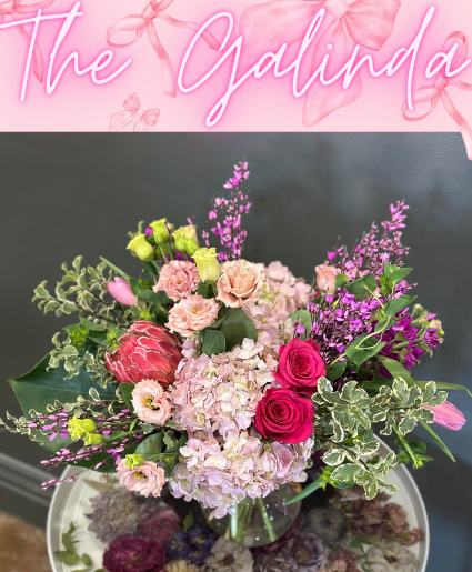 The Galinda All pink arrangement featuring roses, tinted solidago, hydrangeas, lisianthus, stock, and protea 