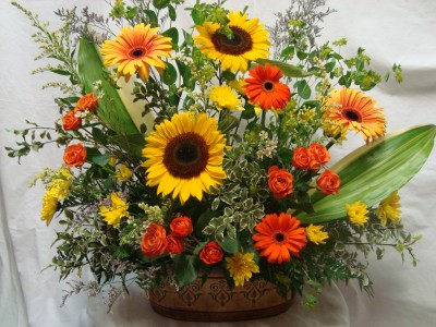 Beautiful arrangement of oranges, yellows, and greens in a nice keepsake Tin container.
